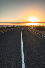 Fototapeta na wymiar Beautiful morning on a road through the dunes. Sunrise over a road with clouds. Corralejo National Park, Canary Islands, Spain