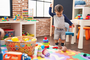 Adorable hispanic toddler standing with serious expression at kindergarten