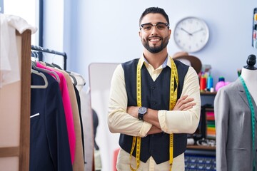 Young arab man tailor smiling confident standing with arms crossed gesture at clothing factory