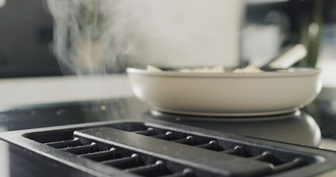 Potatoes are fried on a modern induction cooker. Built-in extractor works. Side view