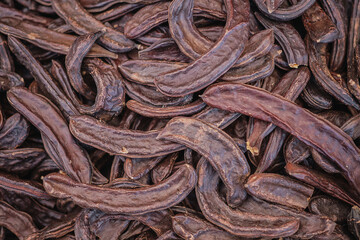 Carob tree pods on a wooden table top view, close-up. Healthy Organic Sweet Carob Pods