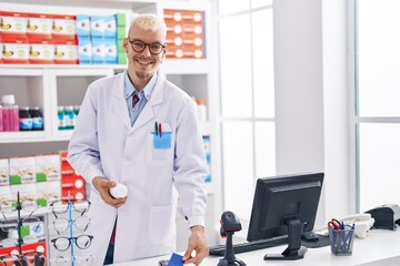 Fototapeta premium Young caucasian man pharmacist holding pills bottle using data phone and credit card at pharmacy