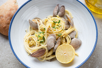 Plate of spaghetti with littleneck clams, chopped parsley and lemon zest, middle closeup, horizontal shot