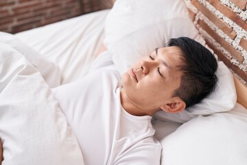 Fototapeta na wymiar Young chinese man lying on bed sleeping at bedroom