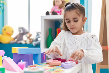 Obraz na płótnie Canvas Adorable hispanic girl playing with toys standing at kindergarten