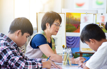 Classroom arts and paints learning of asian boy students and female teacher, soft focus, raising teens concept.