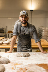 Bakers school, master baker kneading bread dough on table with flour, posing for portrait