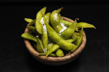 Edamame bean salad with sea salt served in a dark bowl. Isolated on a black background. Restaurant...