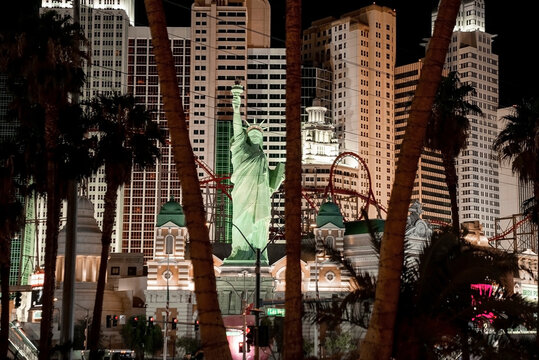 Las Vegas, USA. September 16, 2022. View of Replica of Statue of Liberty and rollercoaster in New York, New York hotel and casino. Illuminated buildings in Las Vegas city seen through trees at night.