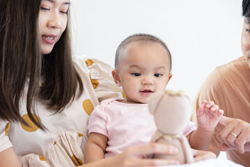 Toddlers are feeling safe and happy with their parents' care in bed at home. Asian family takes care of their children's health with love. Young children are learning to develop their brains.