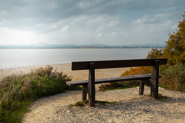 Fototapeta na wymiar Back view of old wooden bench on coast of lake.