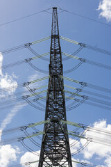 silhouette of power pylon against blue cloudy sky