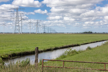 Dutch countryside in Groningen with windturbines and power pylons