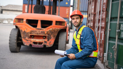 Engineer or foreman checking inventory or task details at container yard warehouse while wearing...
