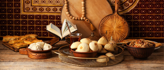 Traditional Eastern dishes with Quran on wooden table