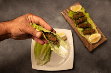 raw meatballs, meatballs in hand, man eating meatballs, meatballs in lettuce