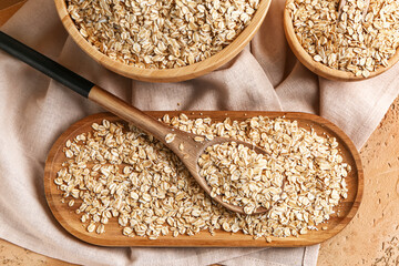 Plate and bowls with raw oatmeal on color table, closeup