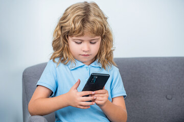 Fototapeta premium Boy communicates on Internet. Child gadget addiction, insomnia. Little boy using smartphone, looking at screen, child holding phone in hands, playing mobile device game, watching cartoons online
