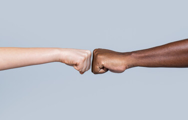 Black African American race male and woman hands giving a fist bump, multiracial diversity, immigration concept. Closeup of multicultural friends giving fist bump to each other - obrazy, fototapety, plakaty