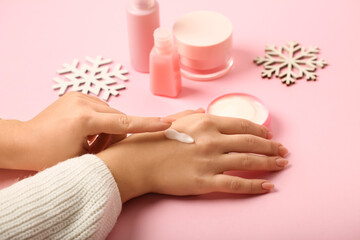 Obraz na płótnie Canvas Woman applying cream onto her hand on pink background, closeup