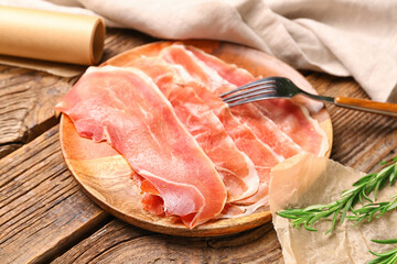 Plate with slices of tasty ham on wooden background