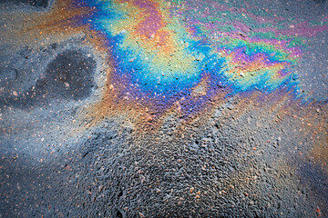Oil stain on the asphalt, rainbow-shaped colored gasoline stains on an asphalt road