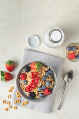 Cereal bowls with fruit and a bottle of milk on a gray napkin on a white table. Healthy eating concept. Front view.