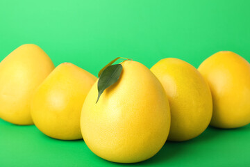 Yellow pomelo fruits on green background, closeup