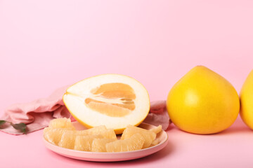 Plate with pomelo fruit and slices on pink background, closeup
