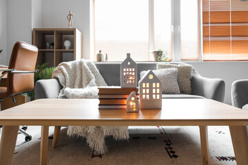 House shaped candle holders and books on table in living room