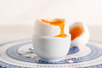 Blue plate with soft boiled egg in holder on light background