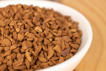 Fragrant instant coffee in a white ceramic saucer on a wooden table.
