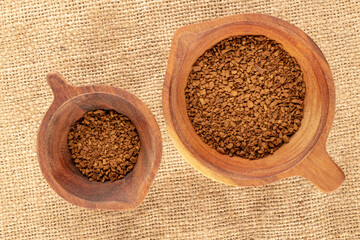 Fragrant instant coffee in two wooden cups on a jute cloth, macro, top view.