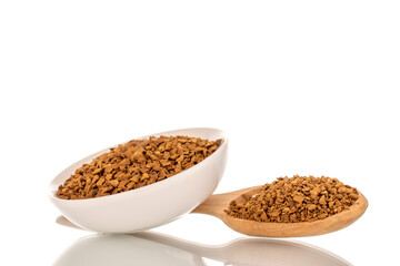 Fragrant instant coffee with wooden spoon and white ceramic saucer, macro, isolated on white background.