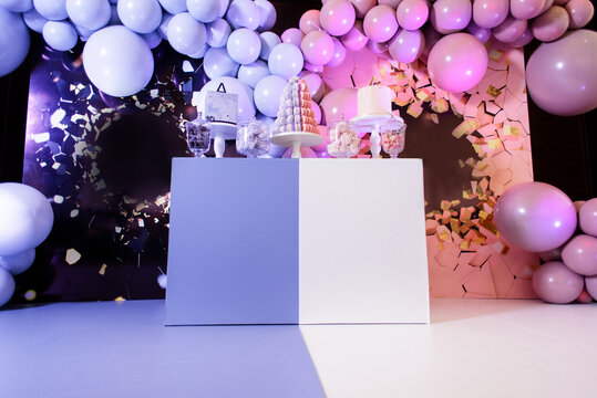 Photo zone and candy bar for a gender party made in pink and blue colors.
