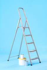 Maintenance ladder and cans of paint on blue background