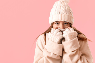 Frozen young woman in winter clothes on pink background, closeup