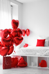 Interior of light bedroom decorated for Valentine's Day with balloons and gifts