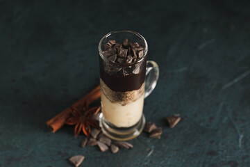 Shot of delicious pudding with chocolate, cinnamon and anise on black table