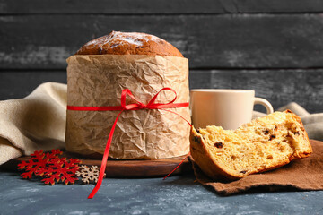 Panettone with cup and snowflakes on dark table, closeup