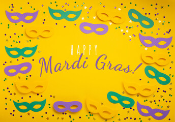 Mardi Gras gold color beads with Masquerade festival carnival masks and golden, green, purple confetti on yellow background.