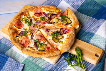 Bacon Pizza with Pickled Cucumbers on Wooden Cutting Board.