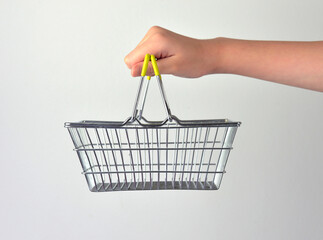 Hand holding empty chrome basket for shopping on white background