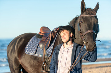 Young smiling man standing together with horse on sea beach