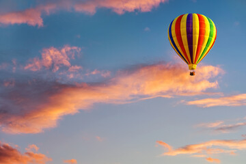 A hot air balloon in the sky on the background of bright sunset.