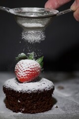strawberry and chocolate cake being sprinkled with icing sugar