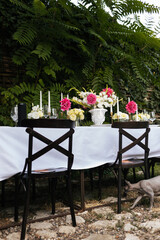 Flowers decorations on the table. Beautiful plates and candles.  Table setting by the pink, yellow. white flowers outdoor.