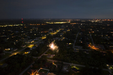 Aerial view of bright fireworks exploding with colorful lights over suburban houses in residential...