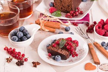 Chocolate sponge cake with fresh fruit on white dish.