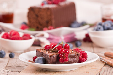 Chocolate sponge cake with fresh fruit on white dish.